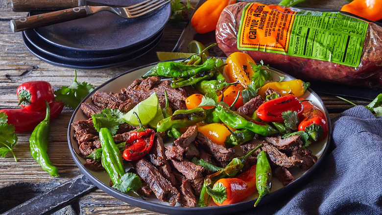 a plate of carne asada with peppers and limes and a package of Trader Joe's Carne Asada Autentica behind it.