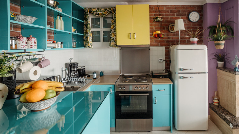 A modern kitchen with robin's egg blue cabinets and shelving, and one yellow cabinet as an accent