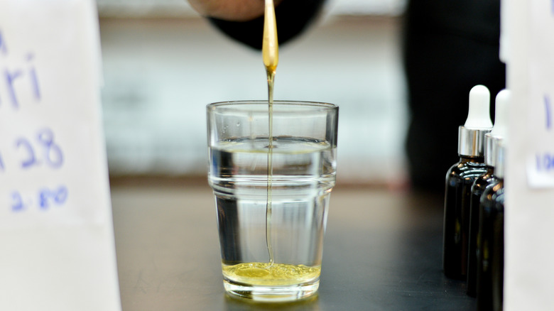 A person testing honey by pouring it into clear water.