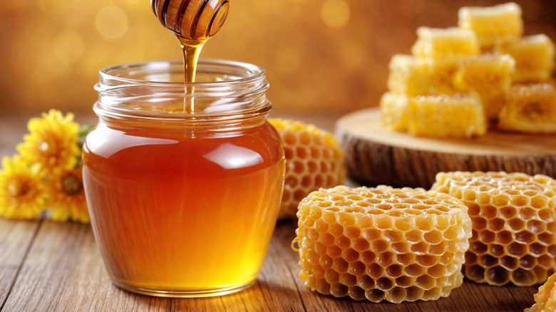 a jar of real honey surrounded by honeycomb