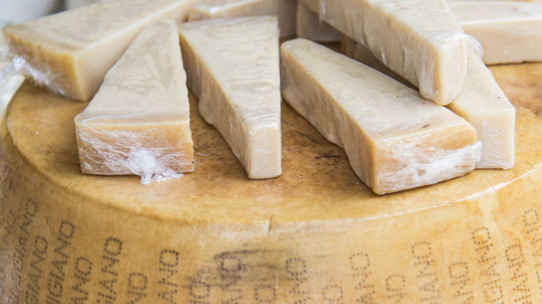 wedges of cut Parmigiano Reggiano cheese sitting atop a wheel of the cheese
