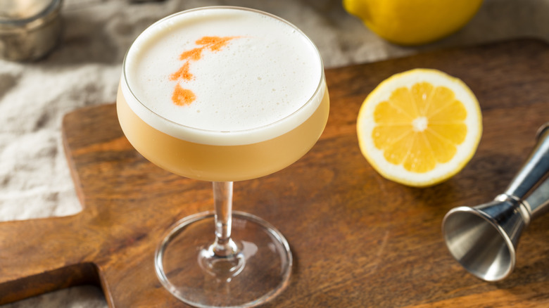 Pisco sour cocktail in a chanpagne glass with lemons