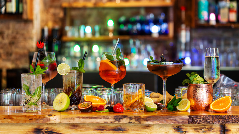 a variety of cocktails lined up on a bar
