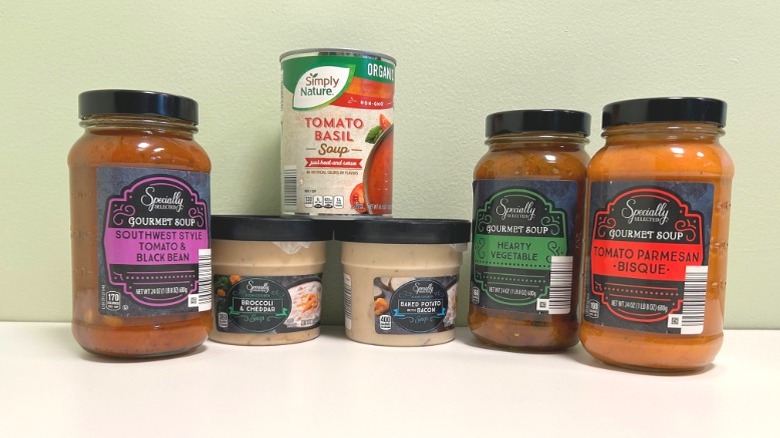 Six containers of Aldi brand soups against a neutral background