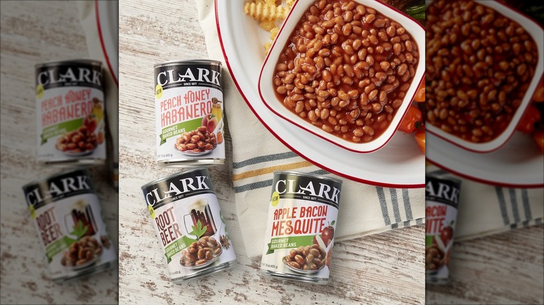 Three different cans of Clark baked beans flavors with square bowl of baked beans