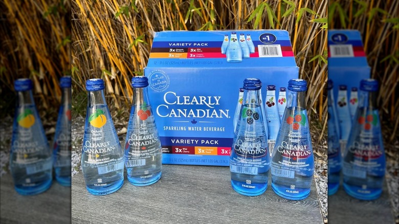 Variety of Clearly Canadian bottles in front of variety box outdoors
