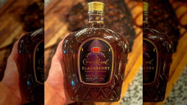 Crown Royal Blackberry in hand in front of blurred barbecue