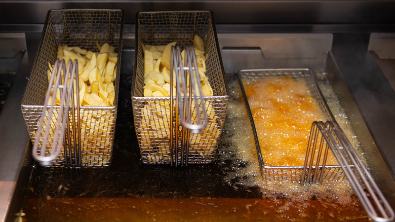 Three batches of french fries being cooked in oil