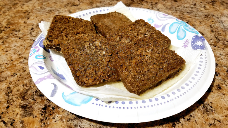 A plate of fried scrapple slices on a marble countertop.