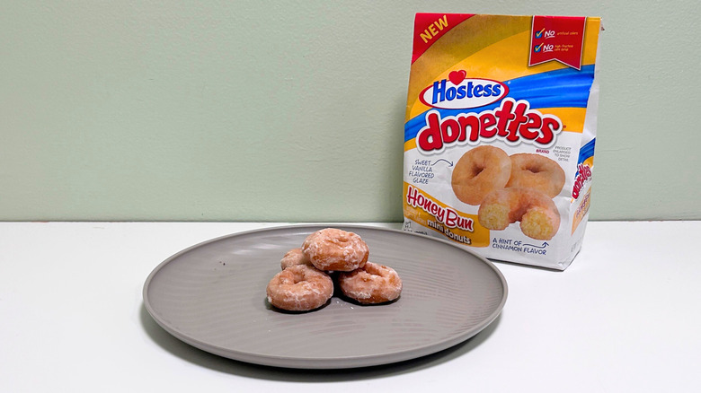 A bag of Hostess Honey Bun Donettes next to a gray plate of donuts