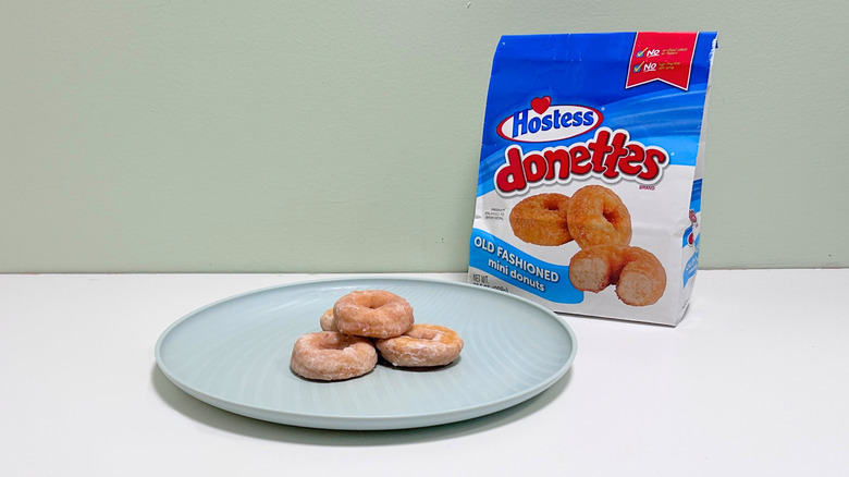 A bag of Hostess Old Fashioned Donettes next to a green plate of donuts