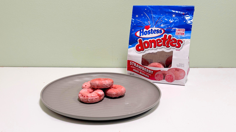 A bag of Hostess Strawberry Donettes next to a gray plate of donuts