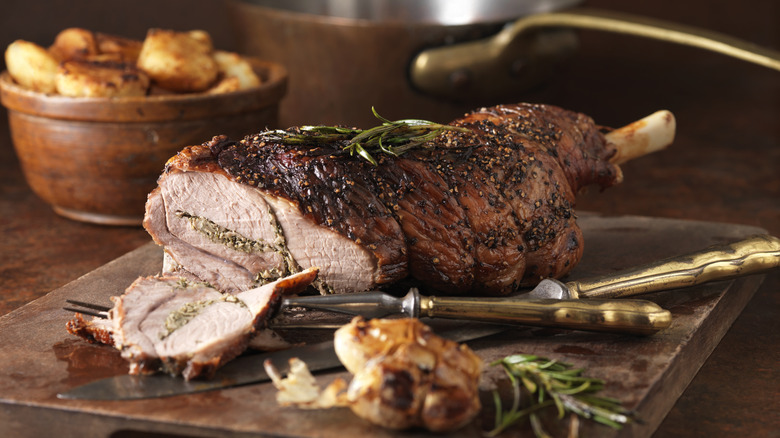 whole roasted leg of lamb with herbs and garlic on a cutting board