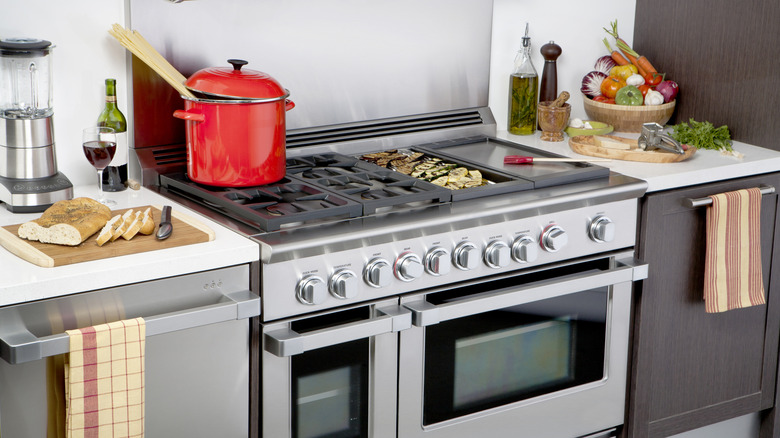 Preparing food on a professional-grade range with four burners, a griddle, a grill top, and two ovens