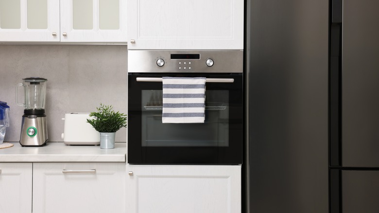 Built-in oven with cabinets above and below, countertop space to the left, and refrigerator on the right