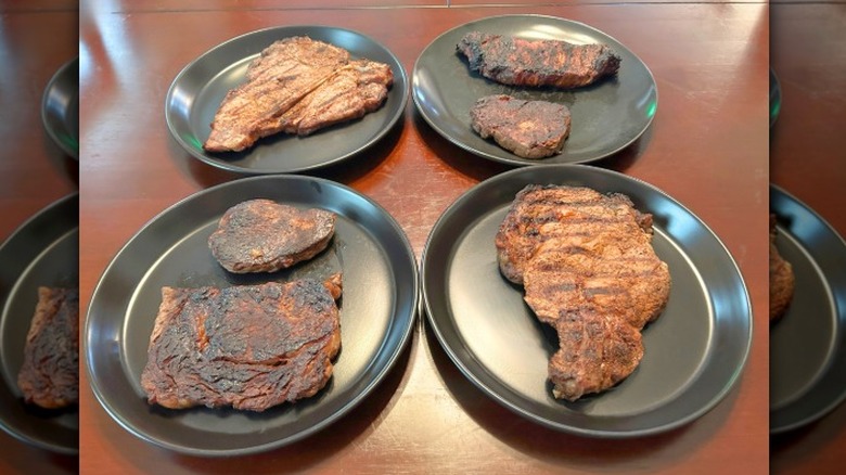 Six Longhorn Steakhouse steaks on black plates against a wood surface
