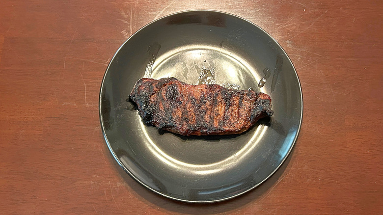 Longhorn Steakhouse strip steak on a black plate against a wooden surface