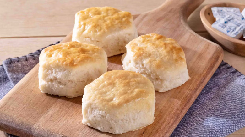 Four buttermilk biscuits arranged on a wooden board.
