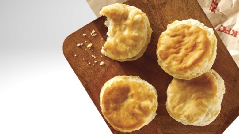 Four KFC biscuits on a wooden board, one with a bite taken out of it