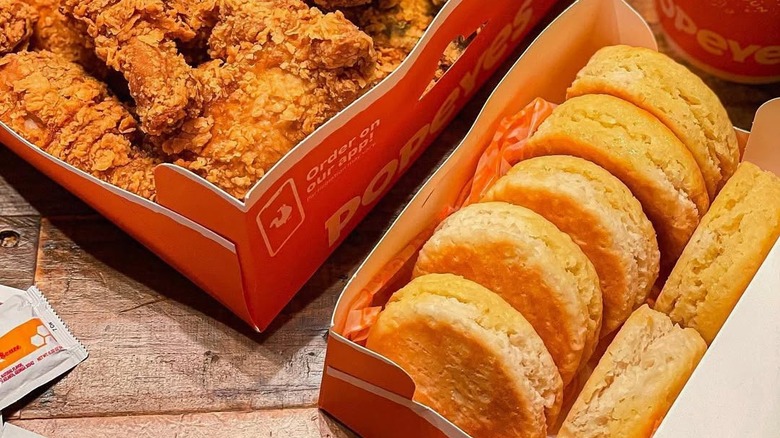 A box of Popeyes biscuits, next to a box of fried chicken.