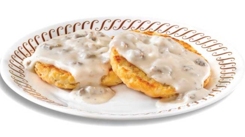 A plate with two biscuits smothered in white gravy.