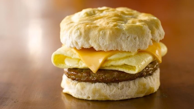 a sausage egg and cheese biscuit on a brown tabletop.