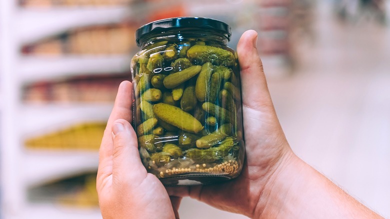 dill pickle jar in hands at grocery store