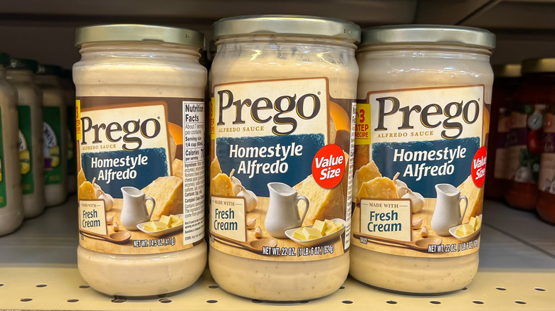 glass jars of Alfredo sauce on a supermarket shelf