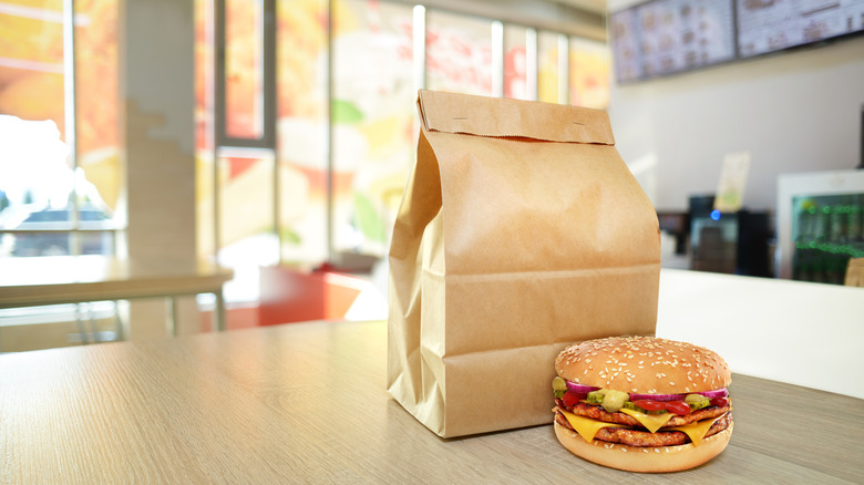 generic fast food restaurant interior with a paper bag and a burger on a table top