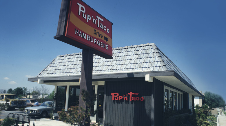 Exterior view of a Pup 'N Taco outlet showing the drive up sign in 1978