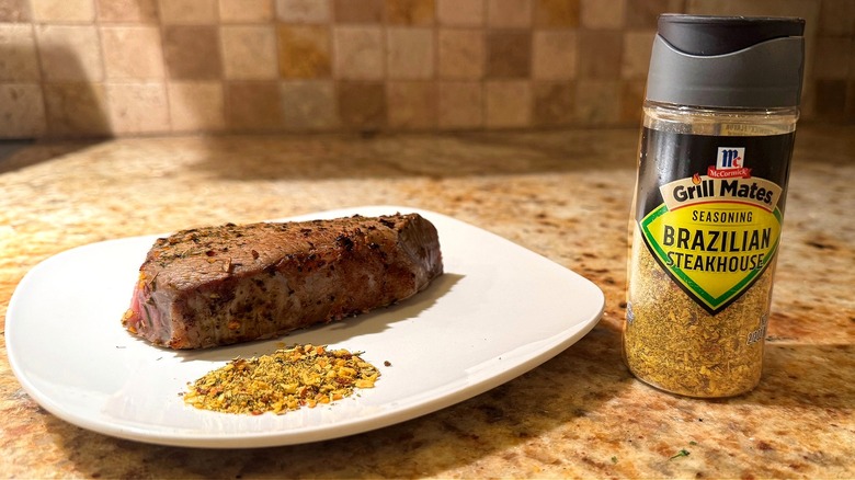 container of seasoning next to plate with steak
