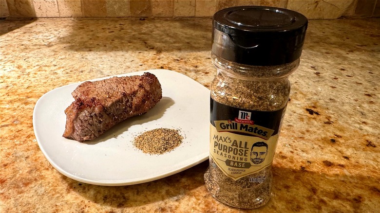 container of seasoning next to plate with steak
