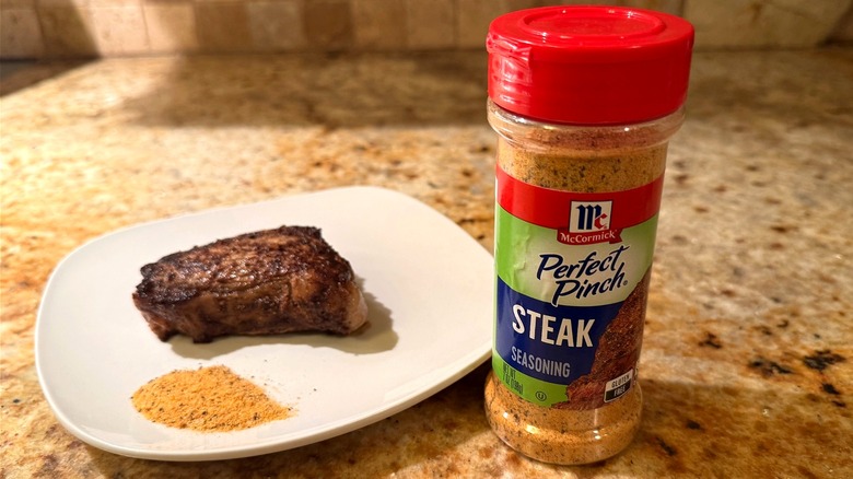 container of seasoning next to plate with steak