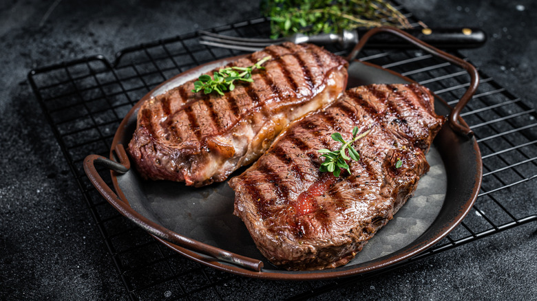 Two grilled flat iron steaks on a cast iron plate