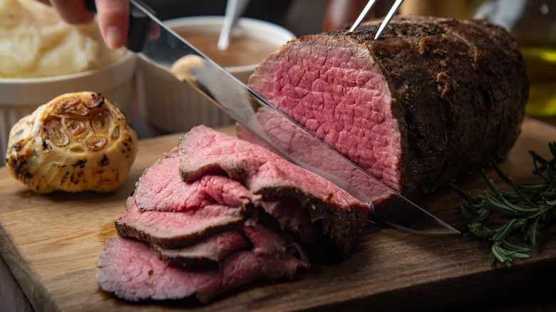 Slicing a roast eye of round beef on a cutting board