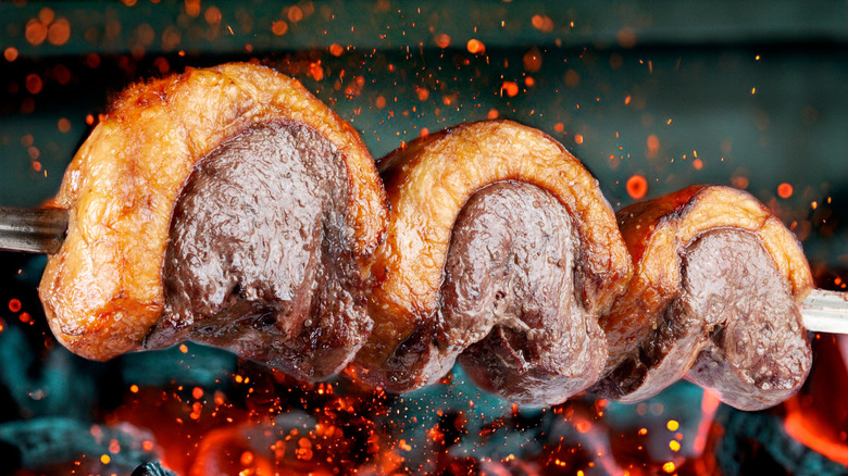 Picanha steak cooking over open flames