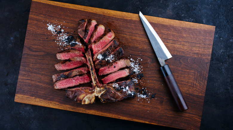 Sliced, grilled porterhouse steak on a cutting board