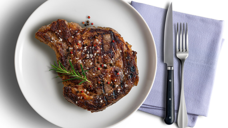 Whole grilled boneless ribeye steak, seared and garnished with rosemary