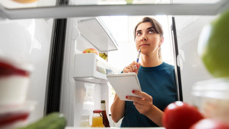 Woman evaluating refrigerator contents