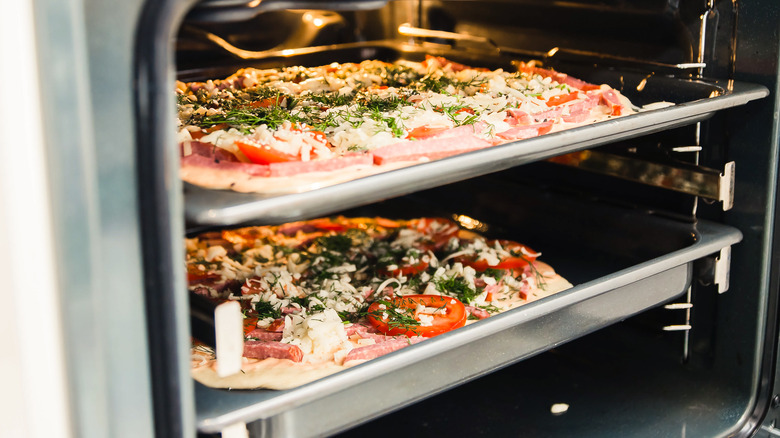 two pizzas baking in oven