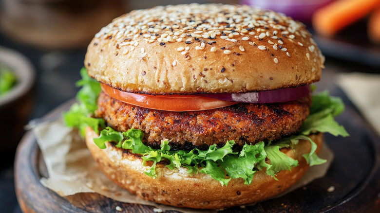 closeup of a veggie burger on a bun with lettuce, tomato, and red onion
