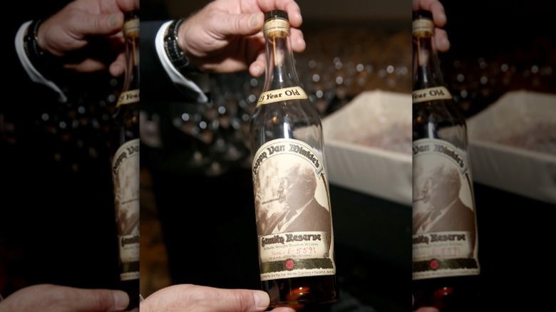 A person holding a bottle of Pappy Van Winkle 23 Year bourbon