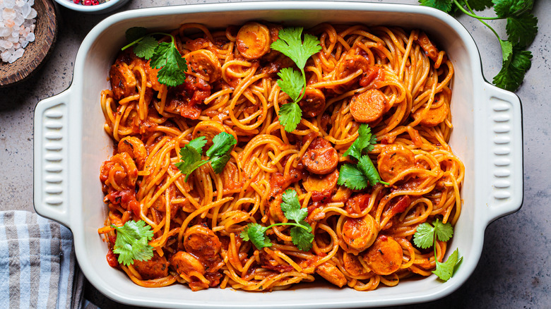 Spaghetti with sausages and cilantro in a baking dish