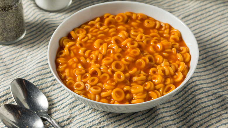 SpaghettiOs in a bowl with spoons on the side on a table