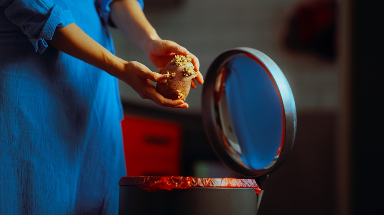 A person throwing away a rotten sprouted potato