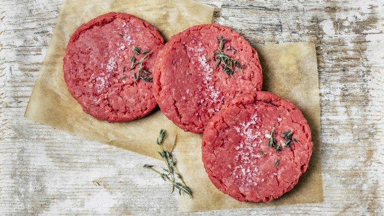 Fully thawed ground beef patties on brown parchment paper