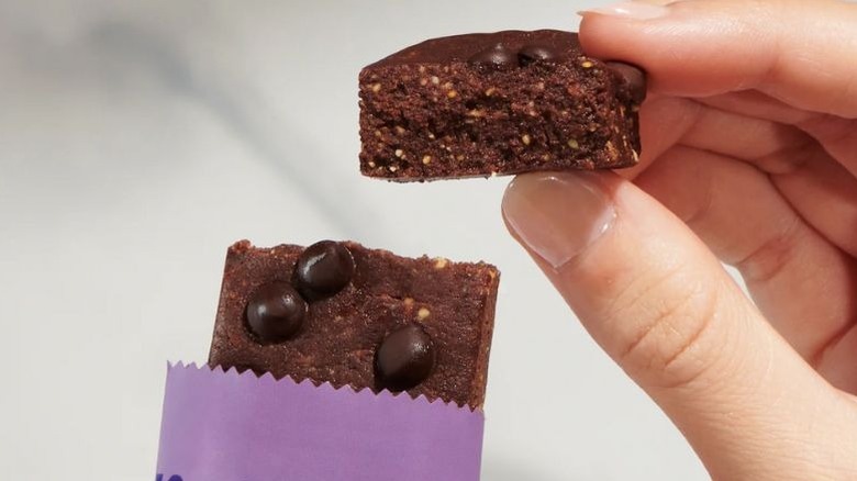 A person holding up a piece of The Perfect Bar Chocolate Brownie