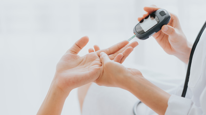 doctor checking blood sugar levels in patient's hand