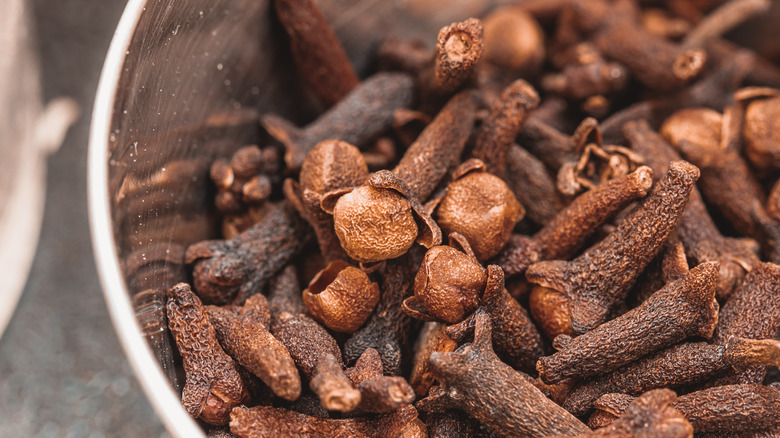 close up of whole cloves in stainless steel bowl