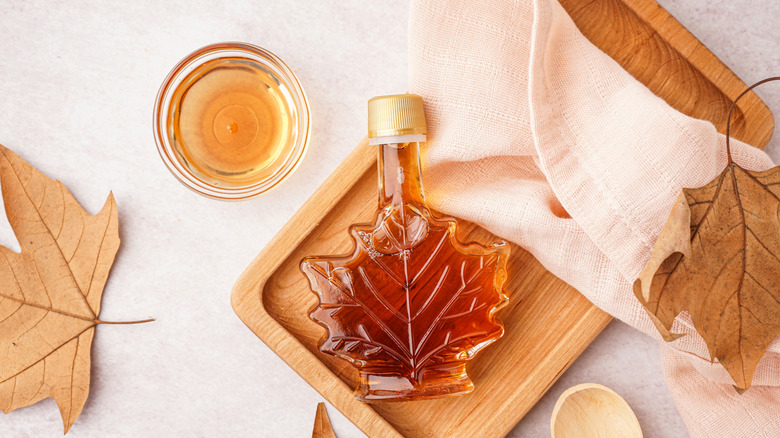 Bottle and glass bowl of maple syrup with maple leaves